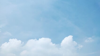 Fototapeta premium Blue sky with fluffy white cumulus clouds on a sunny day. The clouds were white and bright, creating a calm and peaceful atmosphere. Nature background.
