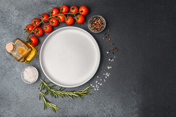 Empty white plate with olive oil rosemary pepper salt and cherry tomatoes on dark table