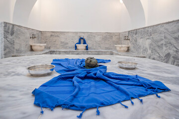 Traditional Turkish Hammam with Marble Platform, Blue Towel and Copper Bowls