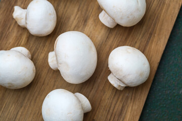 Close-up of champignon mushrooms on wooden surface for texture detail or vegan ingredient concept