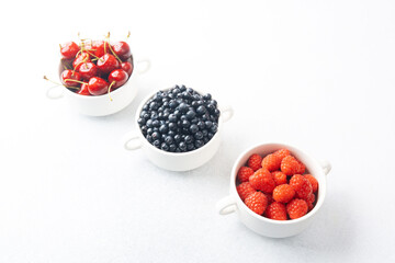 Bowls of raspberries, blueberries and cherries for fruit trio, diet or nutrition concept
