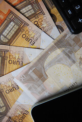 Euro banknotes, phone and calculator on the table