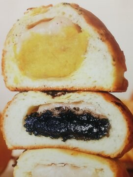 This image displays a stack of three different savory stuffed buns, each cut in half to reveal its unique filling. The buns themselves are a light, golden-brown baked bread, suggesting a soft and fluf