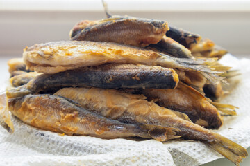 Pile of fish on a napkin. The fish are all different sizes and shapes. The napkin is white and the fish are brown