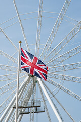 Fototapeta premium Union jack flag flying against a white ferris wheel background. Great Britain concept. Business.
