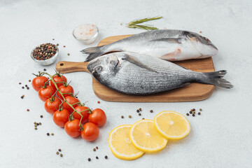 Raw dorado fish with ingredients on wooden cutting board over white background