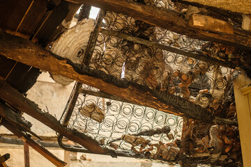 The aftermath of a house fire with charred wood and ruined furniture.