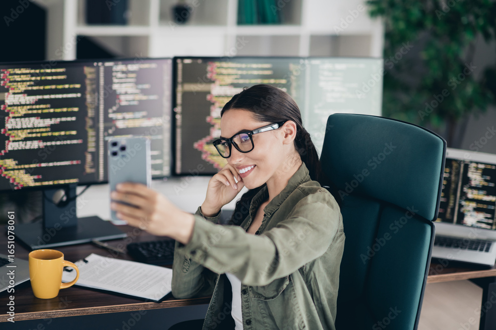 Poster young female programmer taking a selfie in her professional workspace surrounded by computer monitor
