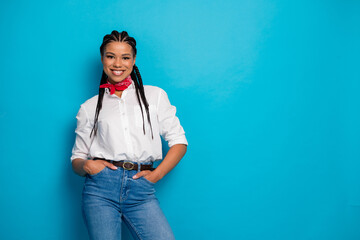 Confident young woman in casual outfit posing against a vibrant blue background, emphasizing her...
