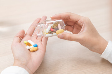 Sick asian young woman, girl holding tablet pill on hand pour capsule from medication bottle, painkiller medicine from stomach pain, headache, pain for treatment, take drug or vitamin, health care.