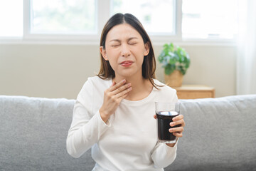 Acid reflux disease, suffer asian young woman, girl hand holding a glass of cola, have symptom...