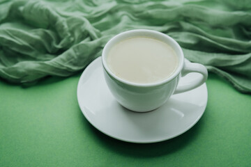 White coffee cup on green textile background with copy space