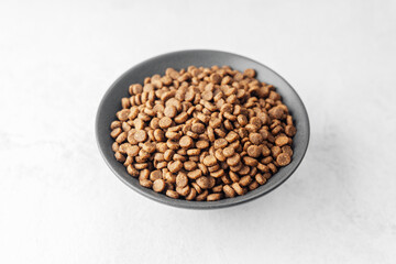 Top view of dry dog food kibbles in black bowl on white background