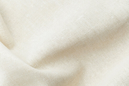 Natural beige fabric textile with soft folds and texture close up