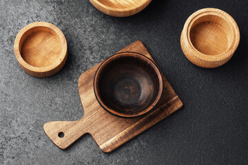 Wooden containers and a small bowl on a cutting board in a kitchen setting