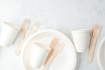 Scattered white paper cups and wooden forks on white disposable plates