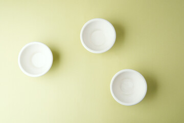 hree white ceramic bowls scattered on green background