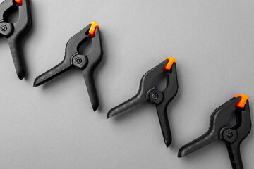 Row of black plastic clamps with orange tips on gray background