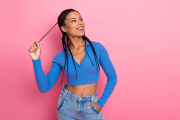 Young woman in blue casual attire looking playful with stylish braids on vibrant pink background