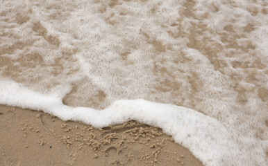 wave of sand washes away a drawing drawn on the sandy shore