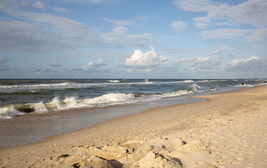 atmospheric photo of the Baltic Sea with golden sand, white waves and blue clear sky with fluffy clouds, beautiful sea landscapes