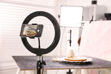 Shooting tasty pie and milk with smartphone in studio, selective focus. Professional food photography
