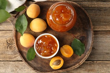 Tasty apricot jam and fresh fruits on wooden table, flat lay