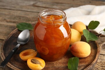 Tasty apricot jam and fresh fruits on wooden table, closeup