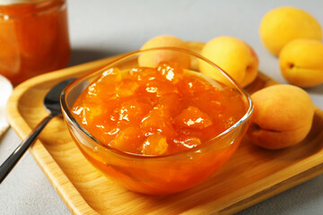Tasty apricot jam and fresh fruits on light grey table, closeup