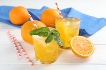 Refreshing soda water with orange slices in glasses, mint and fresh fruits on white wooden table,...