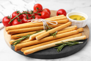 Delicious grissini sticks and rosemary on light table, closeup