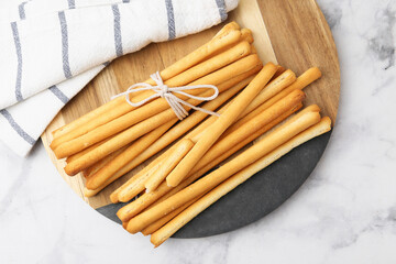 Delicious grissini sticks and napkin on light marble table, top view