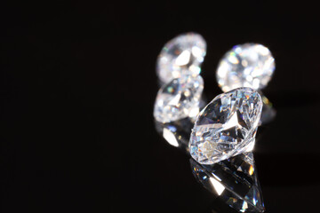 Shiny diamonds on mirror surface against black background, closeup. Space for text