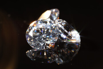 Shiny diamonds on mirror surface against black background, closeup