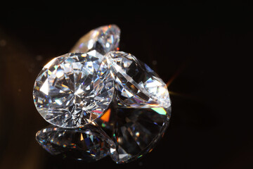 Shiny diamonds on mirror surface against black background, closeup