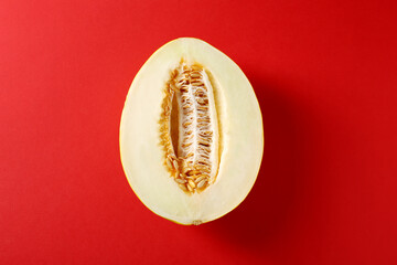Half of ripe melon on red background, top view