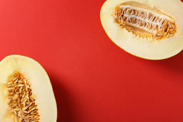 Halves of ripe melon on red background, flat lay. Space for text