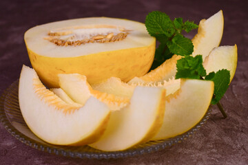 Sweet melon cut into pieces on dark background.
