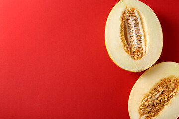 Halves of ripe melon on red background, flat lay. Space for text