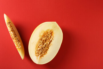 Cut fresh ripe melon on red background, flat lay. Space for text