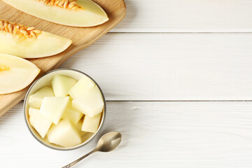 Cut ripe melon on white wooden table, flat lay. Space for text