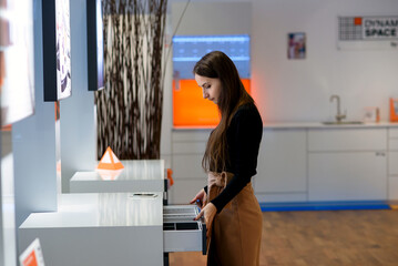 A female designer in a furniture store choosing wooden drawer in furniture store.