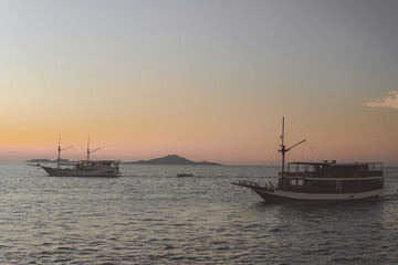 Beautiful scenery of a boat sailing in Labuan Bajo ocean with mountain island on the background.