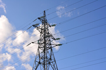 High-voltage power transmission tower against a blue sky with clouds