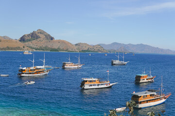 Obraz premium Group of boats sailing in Labuan Bajo ocean with mountain island on the background.