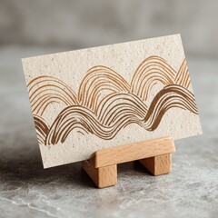 Beige card with brown, wavy design on a wooden stand