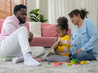 Loving African family enjoying time on living room floor at home. Toddler showing her drawing on small chalkboard to dad