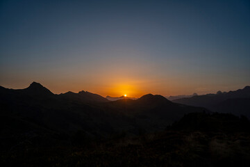 yellow and orange sunrise with layers of the mountains in Damüls Bregenzer Wald in Vorarlberg Austria seen from Portlahorn with negative space for text