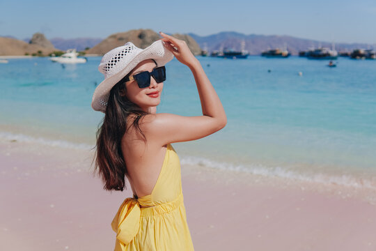 Back view of a carefree young Asian standing and enjoying the pink beach scenery in Labuan Bajo.