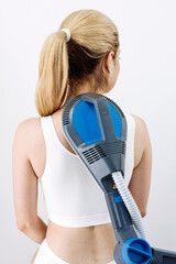 Woman receiving electromagnetic therapy with a high-frequency pulsed magnetic device on her back,...